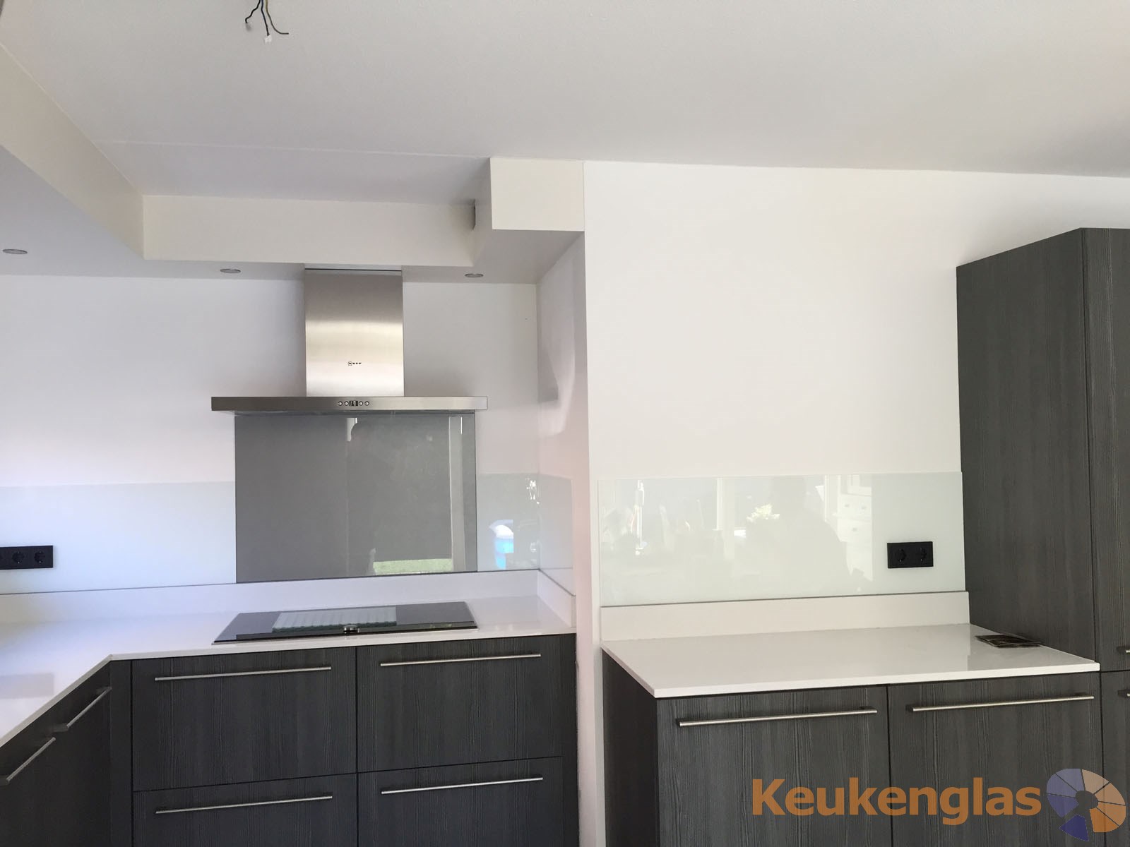 Witte keukenwand van glas met metallic glasplaat achter fornuis Ede 2